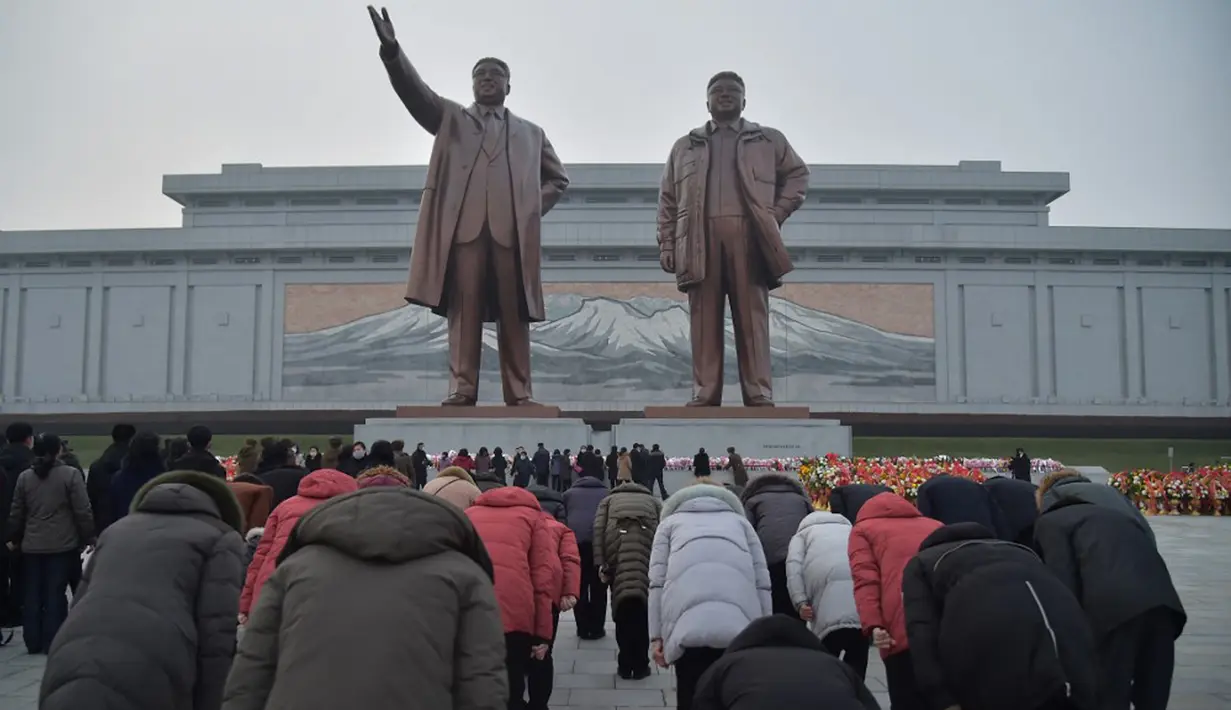 Warg membungkuk memberi hormat di depan patung mendiang pemimpin Korea Utara Kim Il-sung dan Kim Jong-il pada peringatan 10 tahun kematian Kim Jong-il, Pyongyang, Korea Utara, 16 Desember 2021. Kim Jong-il adalah ayah dari pemimpin Korea Utara saat ini, Kim Jong-un. (KIM WON JIN/AFP)