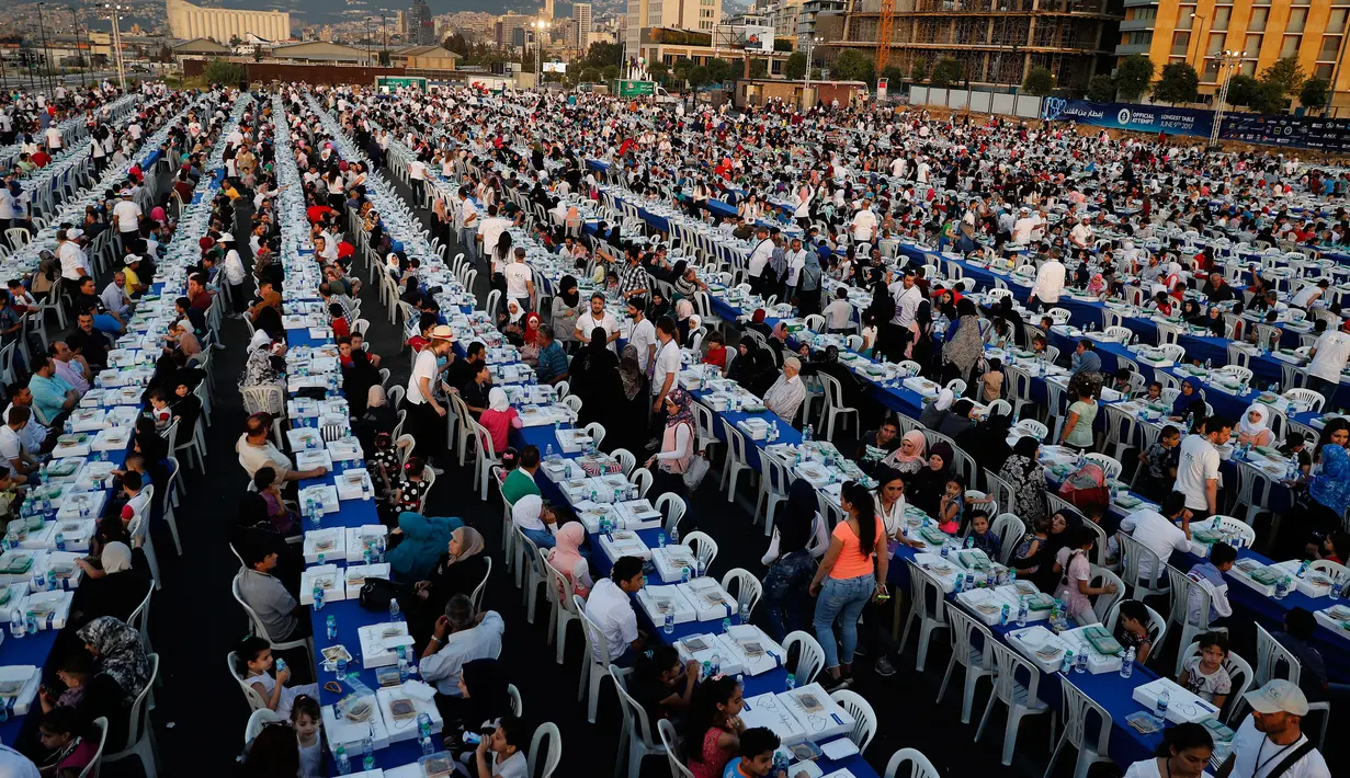 Warga Lebanon beserta yatim piatu dan pengungsi Suriah  berkumpul di sekitar meja-meja Iftar di Beirut Waterfront, Lebanon (9/6). Sebuah organisasi amal Lebanon menggelar buka puasa Ramadan dengan meja terpanjang di dunia. (AP Photo / Hussein Malla)