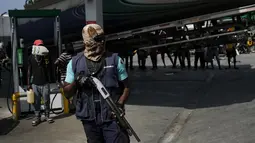 Petugas keamanan bersenjata berjaga ketika sebuah truk tangki membawa bahan bakar ke pompa bensin selama kekurangan bahan bakar nasional di Port-au-Prince, Haiti, Minggu (31/10/2021). Situasi itu telah menambah beban penduduk yang masih berjuang menghadapi krisis ekonomi. (AP Photo/Matias Delacroix)