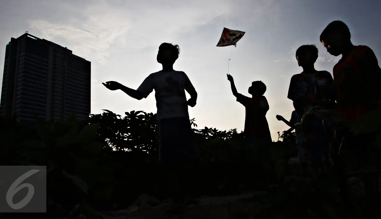 Anak-anak bermain layang-layang di tempat pembuangan limbah bangunan di Gandaria, Jakarta, Jumat (4/3). Keterbatasan lahan bermain membuat mereka bermain di lokasi pembuangan limbah tersebut.  (Liputan.com/Immanuel Antonius)