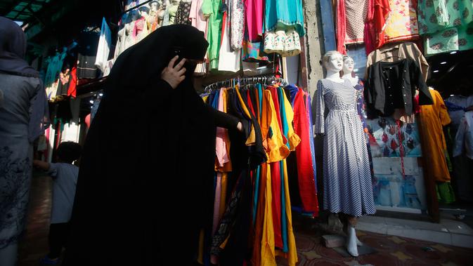 Seorang wanita muslim Kashmir mencari pakaian sebelum Idul Fitri di Srinagar, Kashmir yang dikuasai India (2/6/2019). Idul Fitri, menandai berakhirnya bulan puasa Ramadan. (AP Photo/Mukhtar Khan)