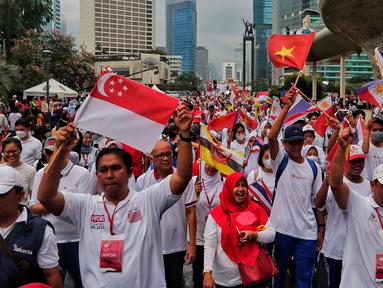 Peserta parade membawa bendera anggota ASEAN saat berjalan dalam Parade Asean di Jalan MH. Thamrin, Jakarta, Minggu (29/1/2023). Acara tersebut merupakan 'kick off' keketuaan Indonesia dalam ASEAN 2023 yang puncaknya akan berlangsung dua kali, yakni Konferensi Tingkat Tinggi (KTT) ASEAN pada Mei 2023 di Labuan Bajo, Provinsi Nusa Tenggara Timur (NTT) dan KTT ASEAN Plus di Jakarta pada September 2023. (Liputan6.com/Angga Yuniar)
