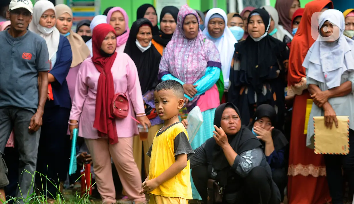 Seorang anak berdiri di antara warga yang antre saat penyaluran bantuan langsung tunai (BLT) Kemensos di Kecamatan Ciseeng, Bogor, Jawa Barat, Senin (28/11/2022). Setiap Keluarga Penerima Manfaat (KPM) mendapat BLT BBM sebesar Rp300ribu, Sembako Rp600 ribu dan bantuan PKH (Program Keluarga Harapan) sebesar Rp600 ribu. (merdeka.com/Arie Basuki)