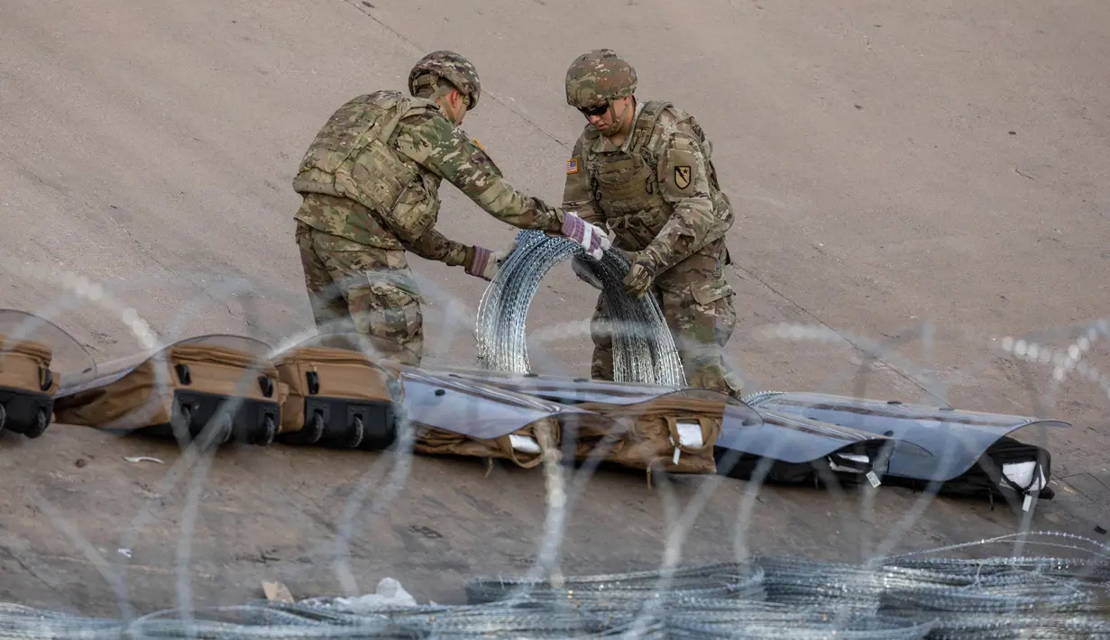 Tentara Pengawal Nasional Texas membuka gulungan kawat berduri di dekat perbatasan AS-Meksiko, Ciudad Juarez, Meksiko, Rabu (21/12/2022). Sebelumnya Mantan Presiden Amerika Serikat Donald Trump menerapkan kebijakan yang diberi nama "Judul 42". (JOHN MOORE / GETTY IMAGES NORTH AMERICA / Getty Images via AFP)