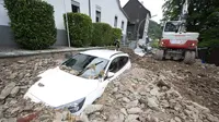 Sebuah mobil tertimbun puing-puing setelah hujan lebat menyebabkan banjir dan kerusakan besar di distrik Hohenlimburg di Hagen, Jerman, Kamis (15/7/2021). (Julian Stratenschulte/dpa via AP)