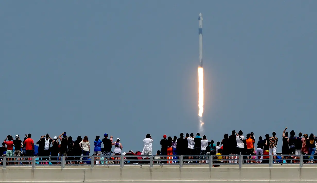Penonton menyaksikan dari jembatan di Titusville ketika SpaceX Falcon 9 lepas landas dari Pusat Antariksa Kennedy di Cape Canaveral, Florida, Sabtu (30/5/2020). Roket itu membawa pesawat luar angkasa Crew Dragon beserta awaknya dua astronot Douglas Hurley dan Robert Behnken.  (AP/Charlie Riedel)
