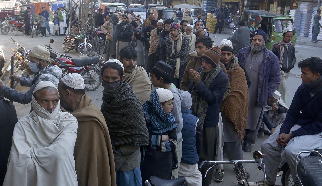 Orang-orang berdiri dalam antrean panjang dan menunggu untuk membeli sekarung tepung terigu bersubsidi dari titik penjualan di Peshawar, Pakistan, Senin, 9 Januari 2023. Orang-orang menderita akibat kenaikan harga tepung terigu di Pakistan baru-baru ini. (AP Photo/Muhammad Sajjad)