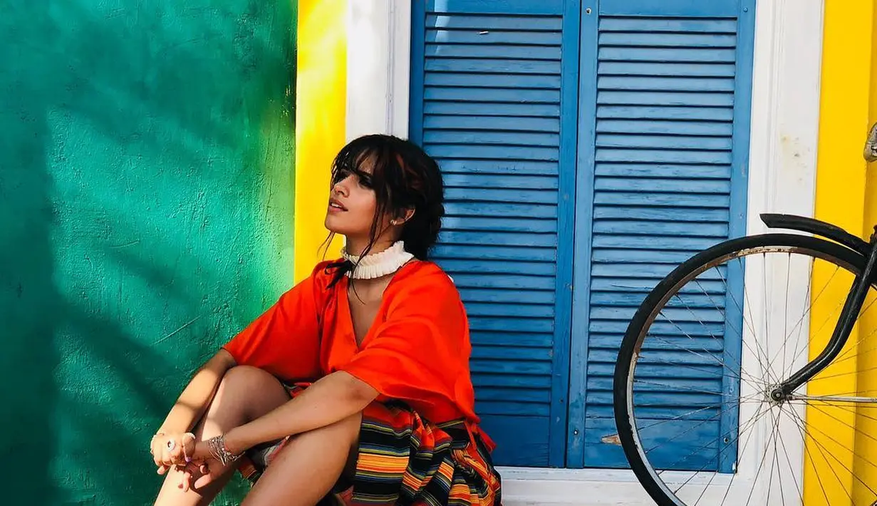 Berpose di Malibu, California, Camila tampak tampil dengan baju berwarna merah dan celana garis garis dilengkapi dengan choker berwarna putih. Dengan latar belakang warna warni dan dilengkapi ban sepeda tua, Camila tampak cantik. (Liputan6.com/IG/@camila_cabello)