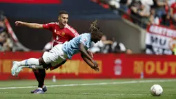 Gelandang Manchester City, Jeremy Doku (kanan) terjatuh saat perebutan bola dengan bek Manchester United, Diogo Dalot pada laga Community Shield 2024 di Wembley Stadium, London, Sabtu (10/8/2024). (AP Photo/David Cliff)