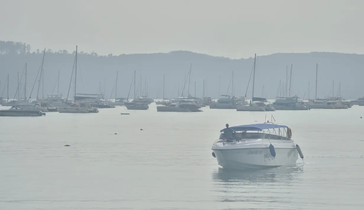Seorang pria berdiri di perahu saat kabut asap menyelimuti dermaga Phuket, Thailand, Jumat (9/10). Ada tujuh provinsi di daerah selatan Thailand yang kena imbas kabut asap Indonesia, namun kondisi di Phuket yang paling parah.(REUTERS/Sooppharoek Teepapan)