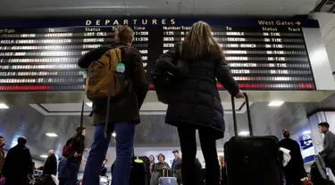 Wisatawan melihat papan jadwal perjalanan di Pennsylvania Station, New York City, Rabu (23/11). Di Amerika Serikat, tradisi mudik dilakukan saat hari perayaan Thanksgiving yang jatuh setiap Kamis keempat di November. (REUTERS/Brendan McDermid)