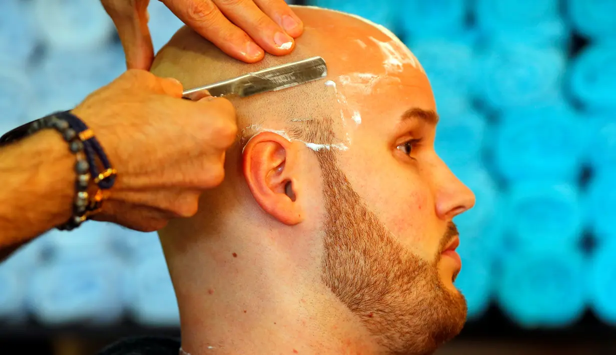 Ibrahim Haji Mohammad saat mencukur rambut pengunjung di toko cukur miliknya di Budapest, Hongaria, 24 Mei 2016. (REUTERS / Laszlo Balogh)