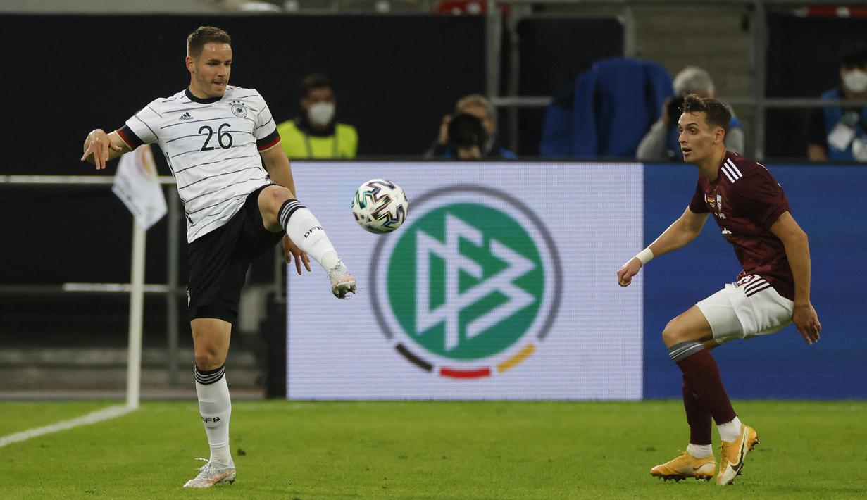 Bek Jerman, Christian Guenter (kiri) mengontrol bola di depan pemain Latvia dalam laga uji coba menjelang Euro 2020 (Euro 2021) di Merkur Spiel Arena, Duesseldorf, Senin (7/6/2021). Jerman menang 7-1 atas Latvia. (AFP/Odd Andersen)