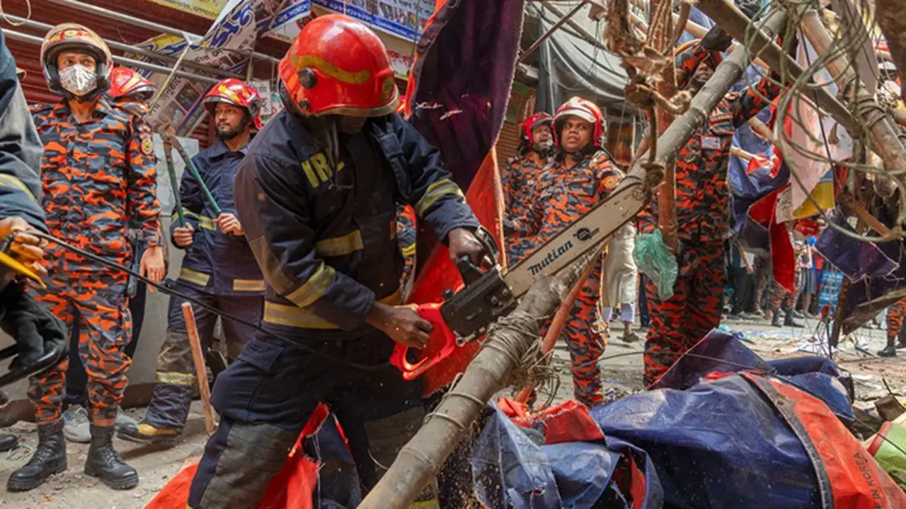 Para petugas penyelamat dan pemadam kebakaran memotong pagar bangunan yang jatuh ke jalan untuk membuka jalur setelah gempa di Dhaka, Bangladesh, Jumat (21/11/2025).