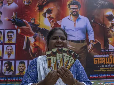 Seorang penggemar memperlihatkan tiket filmnya di dekat poster superstar India Rajinikanth, di luar gedung bioskop untuk merayakan pemutaran film terbarunya "Jailer" di Mumbai, India, Kamis (10/8/2023). (AP Photo/Rafiq Maqbool)