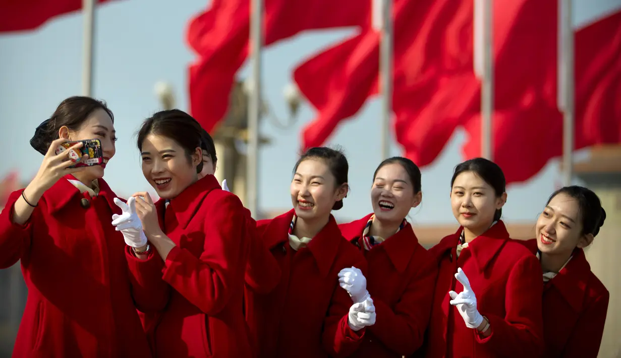 Sejumlah wanita berswafoto di sela penyambutan para peserta Kongres Rakyat Nasional di Beijing, China, Senin (4/3). Para wanita berparas cantik tersebut bertugas menyambut para tamu yang menghadiri kongres. (AP Photo/Mark Schiefelbein)