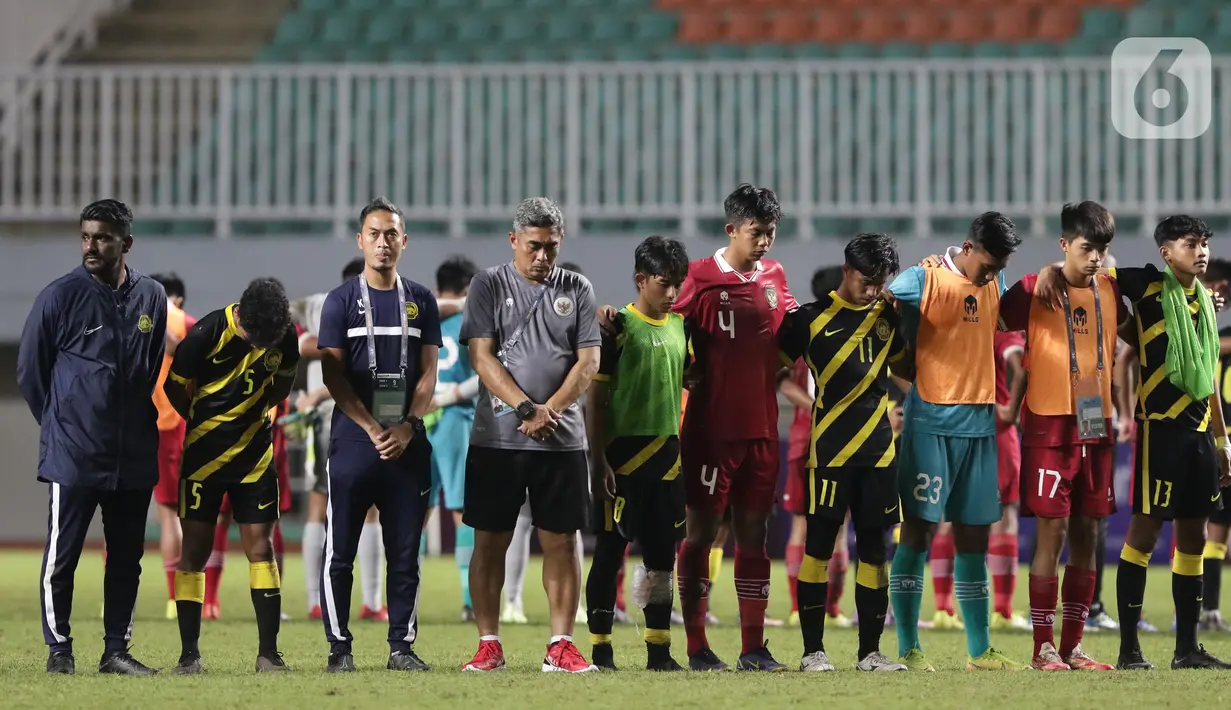 Pemain Timnas U-17 Indonesia dan Malaysia melakukan hening cipta seusai laga terakhir Kualifikasi Grup B Piala Asia U-17 2023 di Stadion Pakansari, Kab. Bogor, Jawa Barat, Minggu (9/10/2022). Timnas U-17 Indonesia finis di peringkat kedua klasemen Kualifikasi Piala Asia U-17 2023 usai menelan kekalahan 1-5 pada laga terakhir Grup B kontra Malaysia. (Liputan6.com/Helmi Fithriansyah)