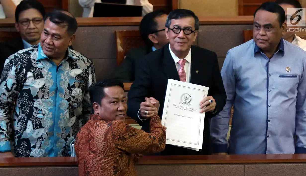 Ketua Baleg DPR Supratman Andi Agtas berjabat tangan dengan Menkumham Yasonna Laoly dalam sidang paripurna ke-9 Masa Persidangan I 2019-2020 di Kompleks Parlemen, Senayan, Selasa (17/9/2019). Rapat Paripurna DPR menyetujui Revisi Undang-Undang Nomor 30 Tahun 2002 tentang KPK. (Liputan6.com/Johan Tal
