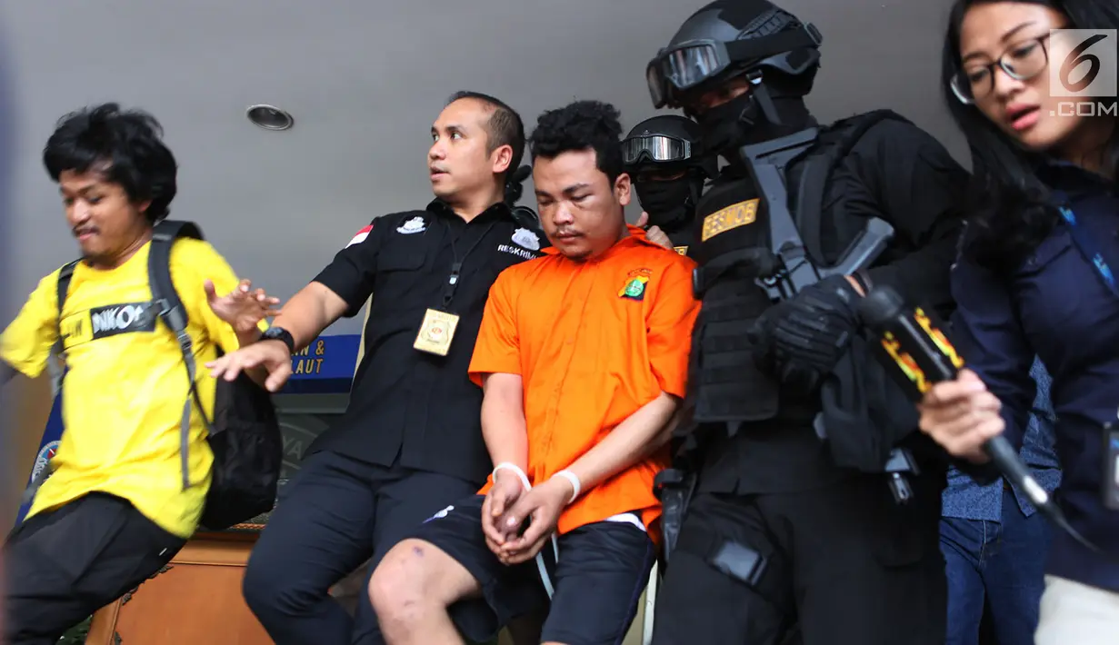 Polisi membawa tersangka pembunuhan satu keluarga di Kota Bekasi saat gelar perkara di Polda Metro Jaya, Jakarta, Jumat (16/11). Tersangka berinisial HS masih memiliki hubungan saudara dengan korban. (Merdeka.com/Imam Buhori)