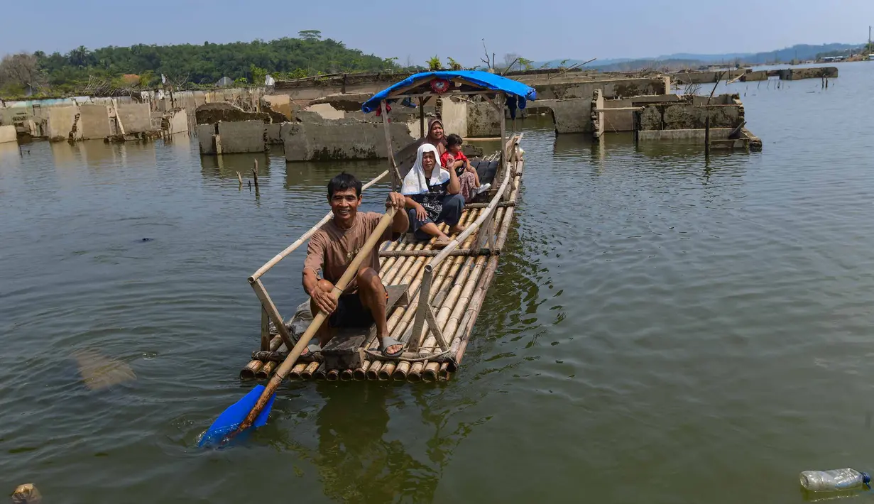 Warga menggunakan perahu  menyaksikan puing-puing bangunan  rumah yang kembali muncul di kawasan Bendungan Karian yang mengering di Kampung Somang, Lebak, Banten, Jumat, 7 Agustus 2026. (KLY/ Arie Basuki)