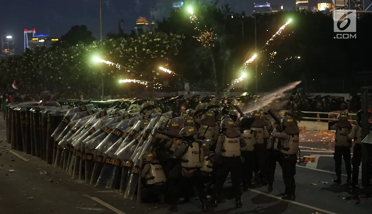 Aparat kepolisian berlindung di balik tameng saat massa aksi melemparkan petasan di sekitar Gedung DPR RI, Jakarta, Senin (30/9/2019). Buntut dari kerusuhan itu, aparat kepolisian melepaskan tembakan gas air mata guna membalas serangan petasan dari pengunjuk rasa. (Liputan6.com/Immanuel Antonius)