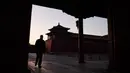 Seorang pria berjalan melewati Forbidden City atau Kota Terlarang yang ditutup di Beijing pada Selasa (4/2/2020). Mencegah korban virus corona bertambah, China menutup  banyak destinasi wisata termasuk Kota Terlarang yang ditutup untuk kunjungan wisatawan sejak 24 Januari 2020 lalu. (GREG BAKER/AFP)