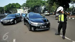 Petugas memeriksa pelat nomor sebuah mobil yang melintas pada tanggal ganjil di Bundaran Senayan, Jakarta, Rabu (31/8). Sejak kemarin petugas mulai memberlakukan sanksi  kepada pengendara yang melanggar aturan ganjil-genap. (Liputan6.com/Gempur M Surya)