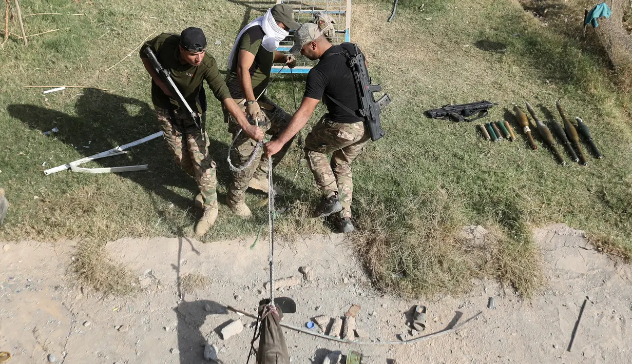 Tiga anggota pasukan Irak menyeret jenazah militan ISIS yang akan dimakamkan di Karamah, selatan Mosul, Irak, (11/11). (REUTERS/Goran Tomasevic)
