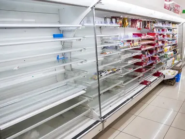 Pembeli memilih bahan makanan dekat rak kosong di sebuah toko, distrik Shinagawa, Tokyo, Sabtu (12/10/2019). Banyak toko-toko perbelanjaan di Jepang yang kehabisan makanan dan minuman akibat warganya yang menimbun makanan untuk menghadapi topan Hagibis. (Odd ANDERSEN / AFP)