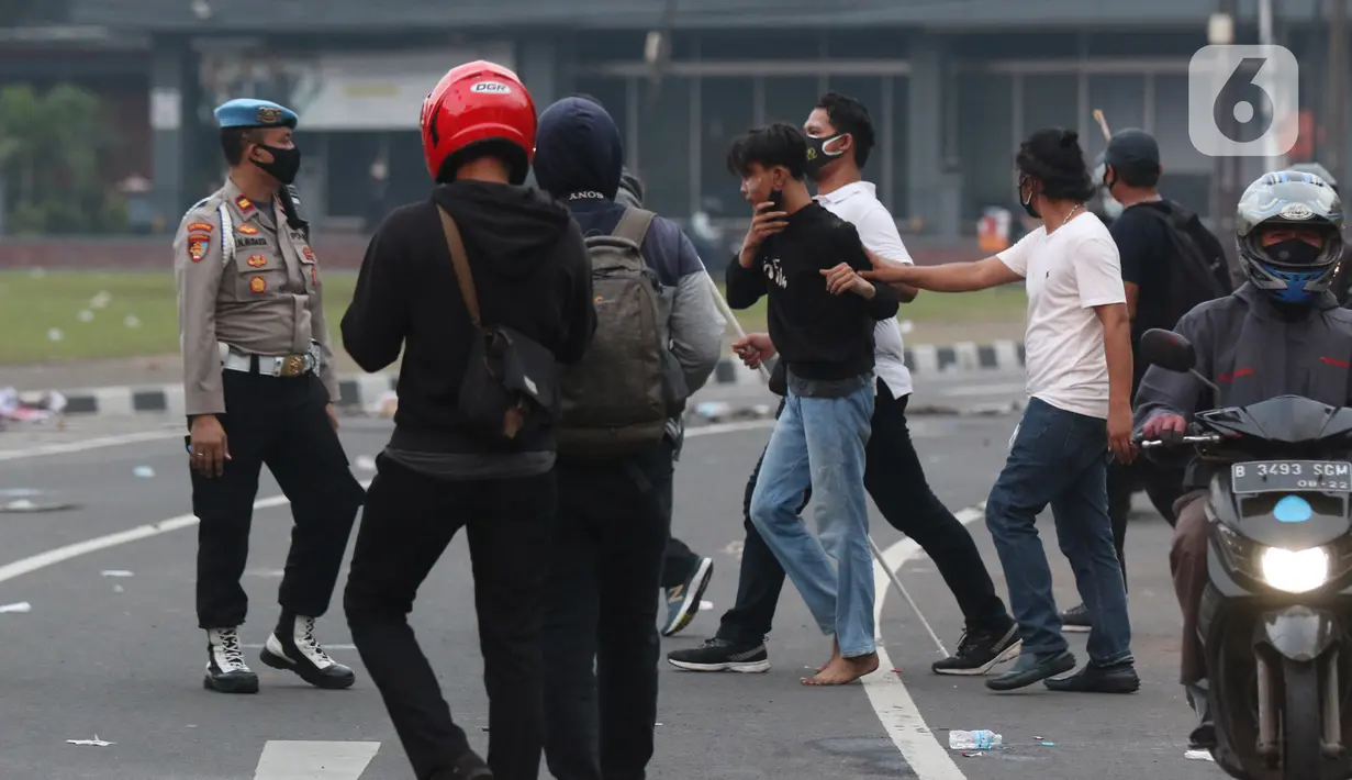 Polisi berpakaian kaus putih mengamankan seseorang yang dicurigai terlibat kericuhan di kawasan Tugu Tani, Jakarta, Selasa (13/10/2020). Sejumlah pemuda diamankan polisi karena dicurigai terlibat kericuhan di kawasan Tugu Tani. (Liputan6.com/Helmi Fithriansyah)
