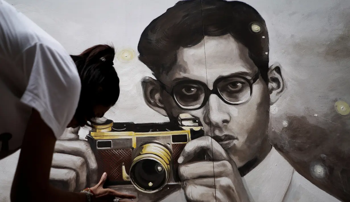 Seorang mahasiswa seni di Thailand melukis potret raja Bhumibol Adulyadej yang sedang memegang kamera, Bangkok, Senin (17/10). Pria yang bergelar Raja Rama IX itu memiliki kecintaan terhadap musik jazz dan dunia fotografi. (Reuters/Athit Perawongmetha)