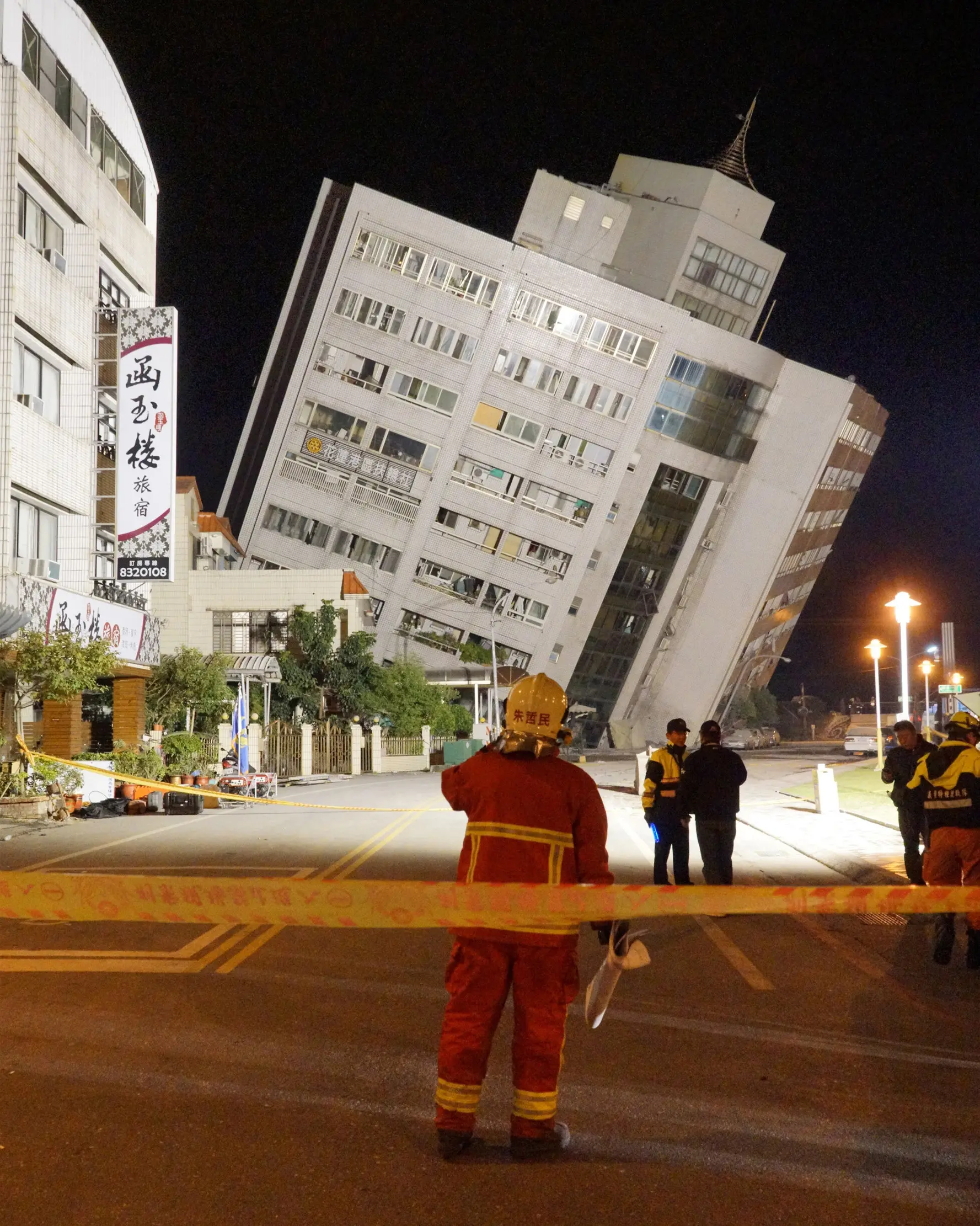 Petugas penyelamat memblokir area di dekat bangunan yang miring karena pondasinya ambruk usai terjadi gempa di Hualien, Taiwan (7/2). (AFP Photo/Paul Yang)