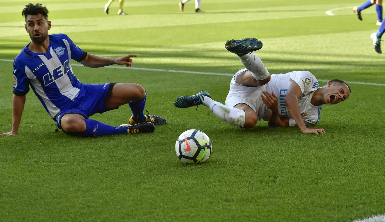 Striker Real Madrid, Lucas Vazquez, terjatuh saat berebut bola dengan bek Deportivo Alaves, Ruben Duarte, pada laga La Liga di Stadion Mendizorroza, Sabtu (23/9/2017). Real Madrid menang 2-1 atas  Deportivo Alaves. (AP/Alvaro Barrientos)