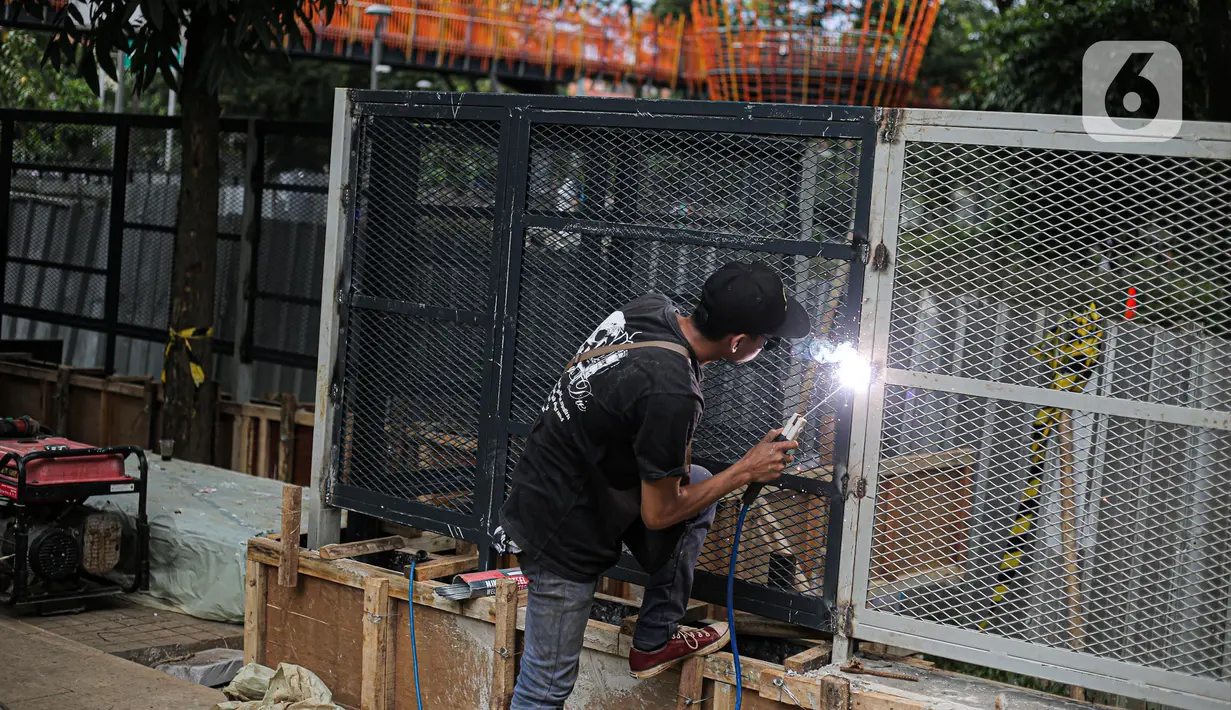 Pekerja melakukan pengelasan saat menyelesaikan pemasangan pagar yang mengelilingi area ruang terbuka hijau (RTH) Tebet Eco Park, Jakarta, Senin (12/12/2022). Pemasangan pagar tersebut membuat taman terkesan lebih rapih dan bagus. (Liputan6.com/Faizal Fanani)