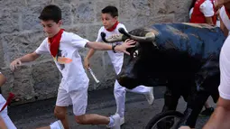 Anak-anak berlarian saat mengikuti Encierro Txiki selama Festival San Fermin di Pamplona, Spanyol (13/7). Small Bull Run hanya dimainkan anak-anak, dan berbeda dengan pria dewasa yang menggunakan banteng sungguhan saat Festival. (AFP Photo/Ander Gillenea)