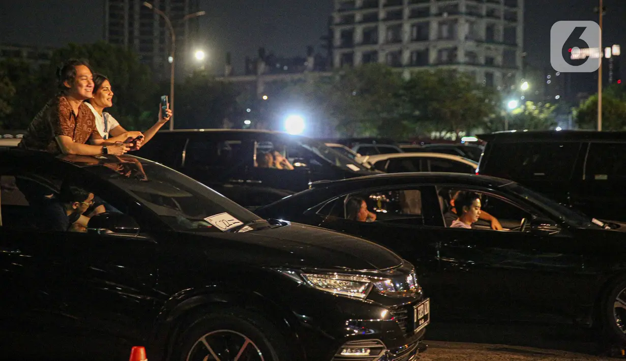 Penonton menikmati konser New Live Experience 2020 pada hari kedua di Parkir Barat JIExpo Kemayoran, Jakarta, Minggu (30/8/2020). Konser musik dengan konsep drive-in tersebut digelar dengan menerapkan protokol kesehatan untuk mencegah penyebaran COVID-19. (Liputan6.com/Faizal Fanani)