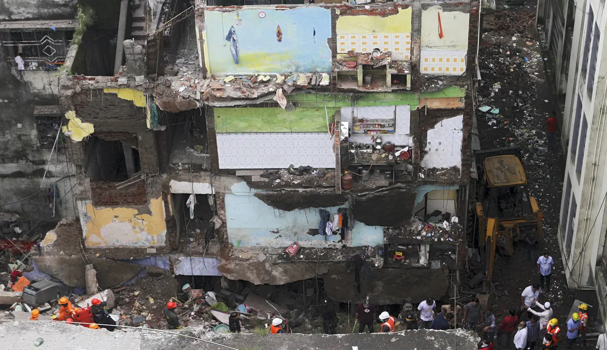 Petugas penyelamat mencari korban di reruntuhan bangunan tempat tinggal tiga lantai yang runtuh di Bhiwandi, India, Senin (21/9/2020). Belum diketahui penyebab kecelakaan, namun kejadian bangunan ambruk sering terjadi di India selama musim hujan yakni antara Juni dan September. (AFP)