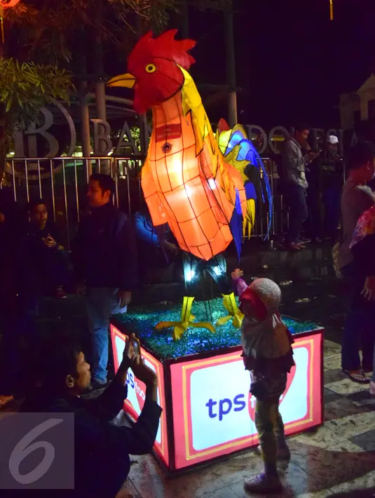 Seorang bocah berpose di dekat lampion berbentuk ayam di kawasan Pasar Gedhe Surakarta saat perayaan Imlek, Surakarta, Sabtu (28/01). Grebeg Soediro adalah  tradisi  tahunan alkuturasi  budaya  Jawa dan  Cina. (Liputan6.com/Gholib)  
