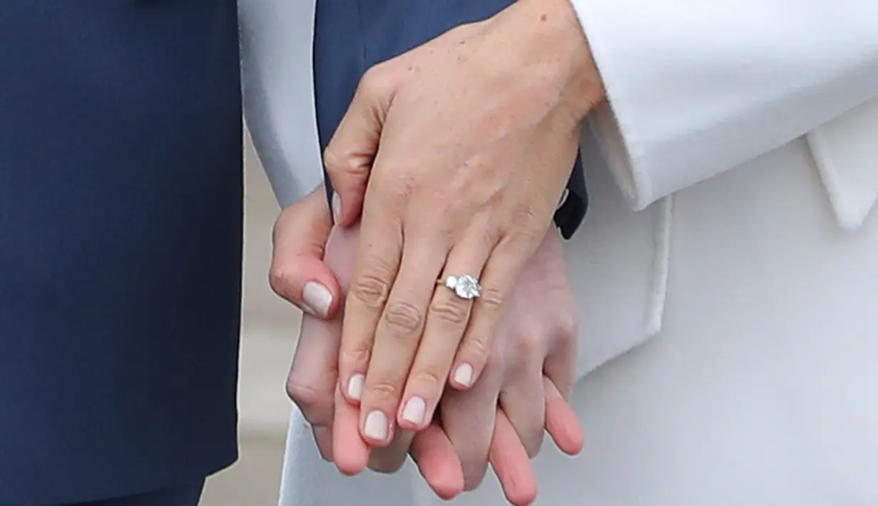 Pangeran Harry dan aktris AS, Meghan Markle menunjukan cincin pertunangan mereka kepada media di Kensington Palace, London, Senin (27/11). Cincin kuning emas pertunangan yang dirancang oleh Harry sendiri itu memiliki tiga berlian. (DANIEL LEAL-OLIVAS/AFP)