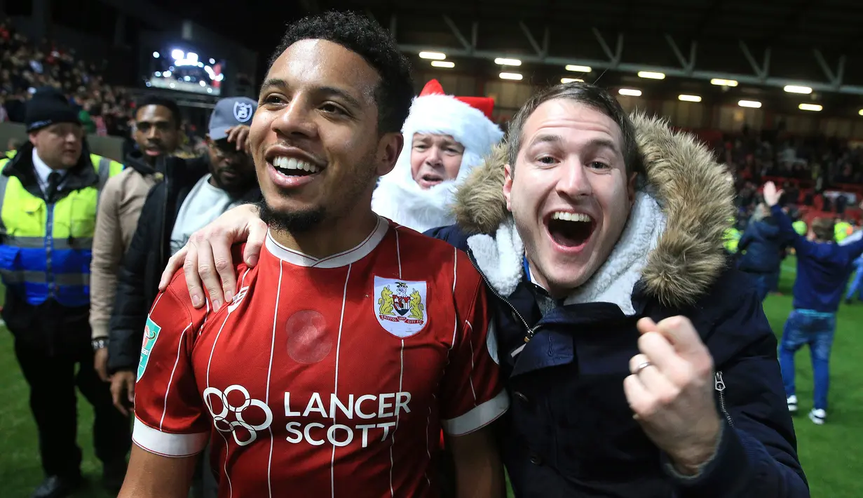 Pemain Bristol City, Korey Smith dan fans merayakan gol ke gawang Manchester United pada perempat final Piala Liga Inggris di Ashton Gate, Kamis (21/12). Klub kasta kedua Bristol City sukses menyingkirkan Manchester United 2-1. (Nick Potts/PA via AP)