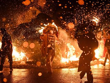 Para pria meletakkan tong-tong mereka yang menyala di atas api di akhir prosesi mereka melalui jalan-jalan selama festival tahunan Allendale Tar Barrel di Allendale, Inggris utara, pada malam hari antara tanggal 31 Desember 2024 dan 1 Januari 2025. (Oli SCARFF/AFP)