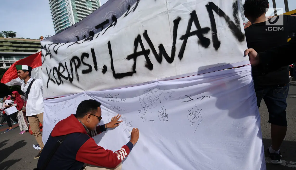 Warga menandatangani spanduk dukungan anti korupsi yang dibentangkan saat Hari Bebas Kendaraan di kawasan Bundaran HI, Jakarta, Minggu (10/12). Aksi dilakukan untuk memperingati Hari Antikorupsi Sedunia, 9 Desember. (Liputan6.com/Helmi Fithriansyah)