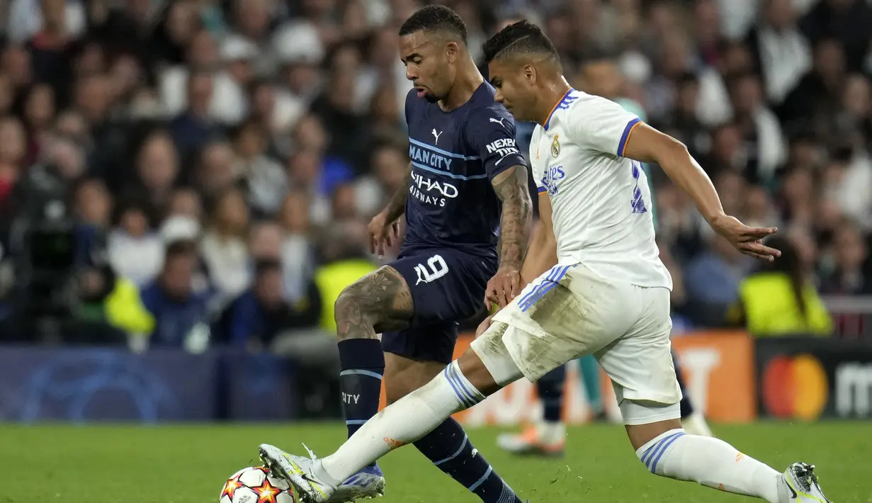 <p>Penyerang Manchester City, Gabriel Jesus berebut bola dengan gelandang Real Madrid, Casemiro&nbsp;pada pertandingan leg kedua semifinal Liga Champions di stadion Santiago Bernabeu, Spanyol, Kamis (5/5/2022). Madrid akan bertemu Liverpool pada babak final. (AP Foto/Manu Fernandez)</p>