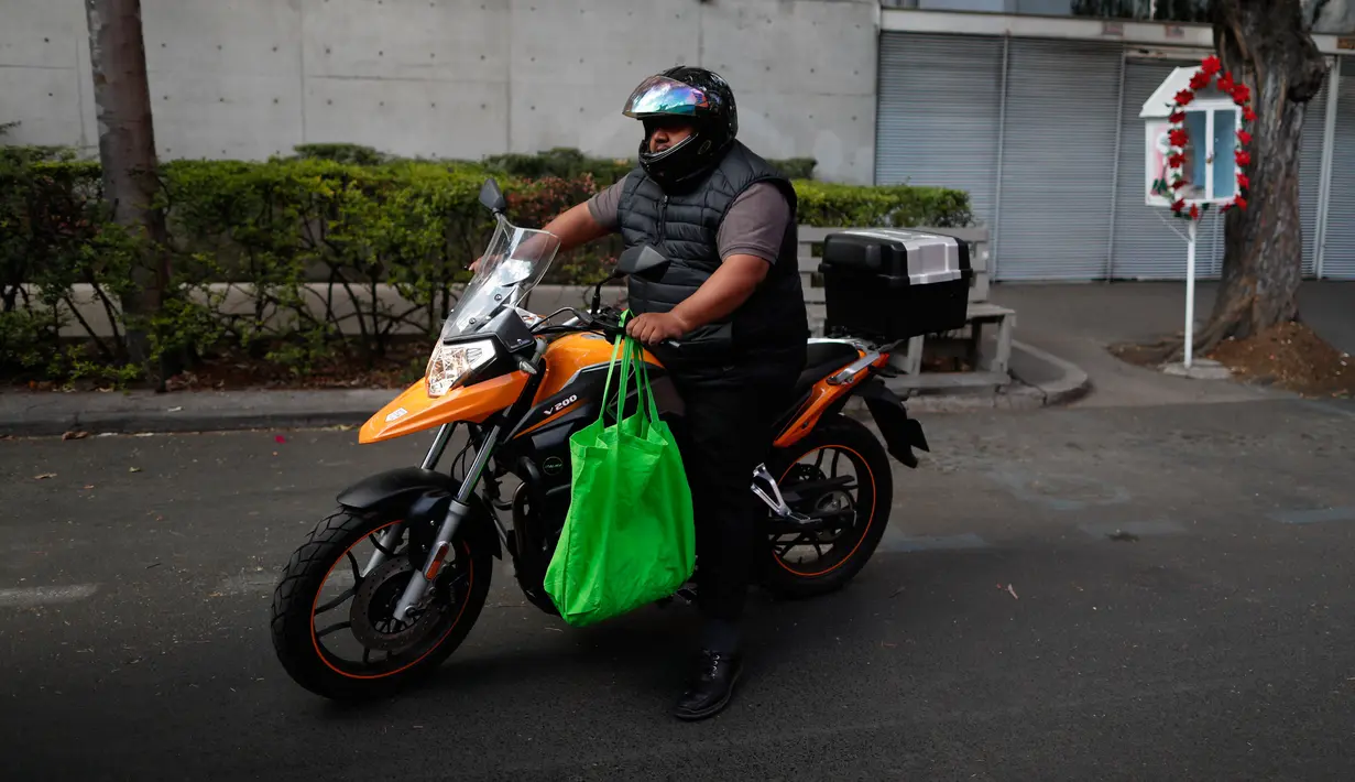 Seorang pria yang mengendarai sepeda motor membawa bahan makanan dalam tas yang dapat digunakan kembali di Mexico City pada1 Januari 2020. Berdasarkan undang-undang baru yang berlaku, pasar swalayan akan didenda jika memberi kantong plastik kepada pelanggan mereka. (AP/Rebecca Blackwell)