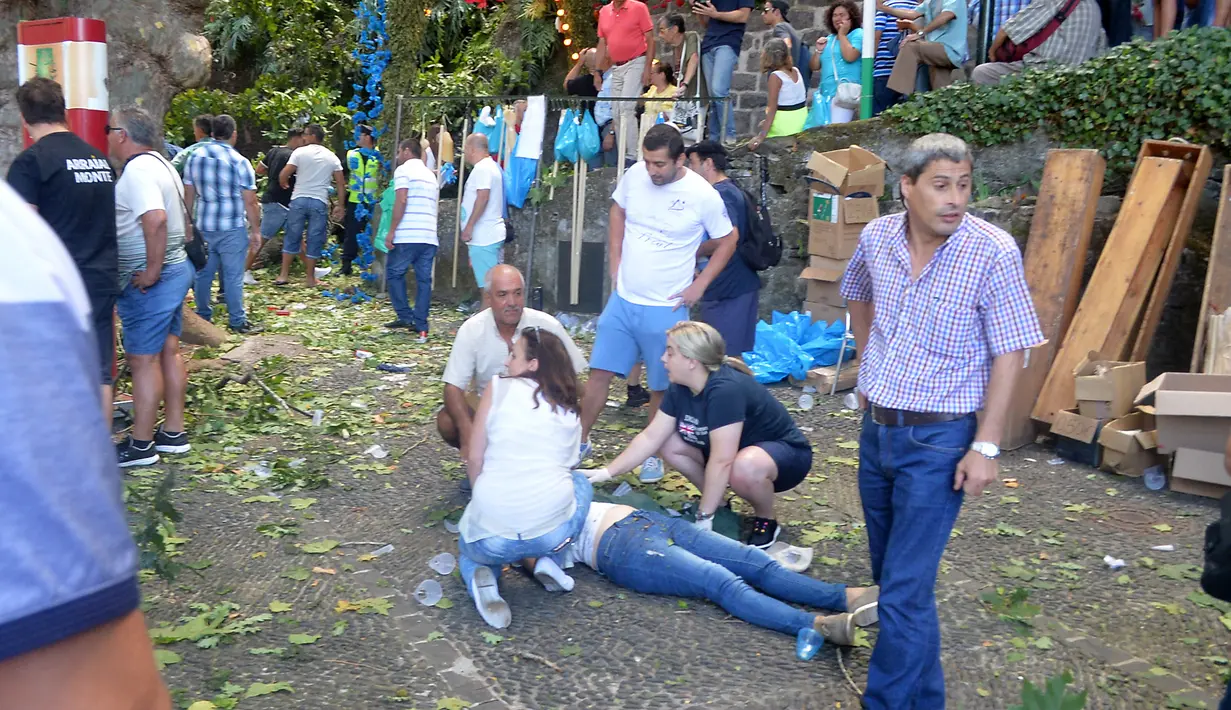 Warga memberi pertolongan kepada korban pohon tumbang di Funchal, Portugal (15/8). Sebuah pohon ek atau oak berusia 200 tahun tumbang dan menimpa kerumunan orang yang berada di sebuah alun-alun di wilayah sub-urban Funchal. (AFP Photo/Rui Silva)