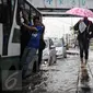 Seorang pejalan kaki sambil menggunakan payung melintasi banjir yang menggenangi jalan di depan Ancol, Jakarta, Kamis (21/4). Hujan deras yang mengguyur sejak semalam menyebabkan beberapa kawasan di Jakarta tergenang banjir. (Liputan6.com/Faizal Fanani) 