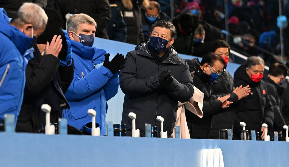 Presiden Komite Olimpiade Internasional (IOC) Thomas Bach (kiri) dan Presiden China Xi Jinping (kanan) bertepuk tangan saat upacara pembukaan Olimpiade Musim Dingin Beijing 2022, di Stadion Nasional, yang dikenal sebagai Stadion Bird's Nest, Beijing, pada 4 Februari 2022. (AFP/Pool/Anthony Wallace)