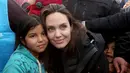 Utusan khusus lembaga pengungsi PBB, aktris Angelina Jolie berpose dengan seorang anak Suriah saat berkunjung ke Kamp Pengungsi Zaatari, di Mafraq, Yordania, Minggu (28/1). Jolie mengaku sedih saat bertemu dengan para pengungsi. (AP Photo/Raad Adayleh)