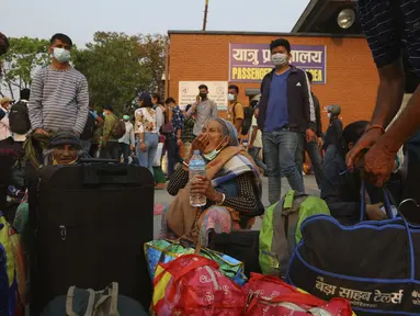 Seorang perempuan meminum obatnya saat menunggu bus untuk kembali ke desa sehari sebelum lockdown di Kathmandu, Rabu (28/4/2021). Puluhan ribu orang meninggalkan ibu kota Nepal sehari menjelang lockdown selama 15 hari yang diberlakukan karena melonjaknya kasus COVID-19. (AP Photo/Niranjan Shrestha)