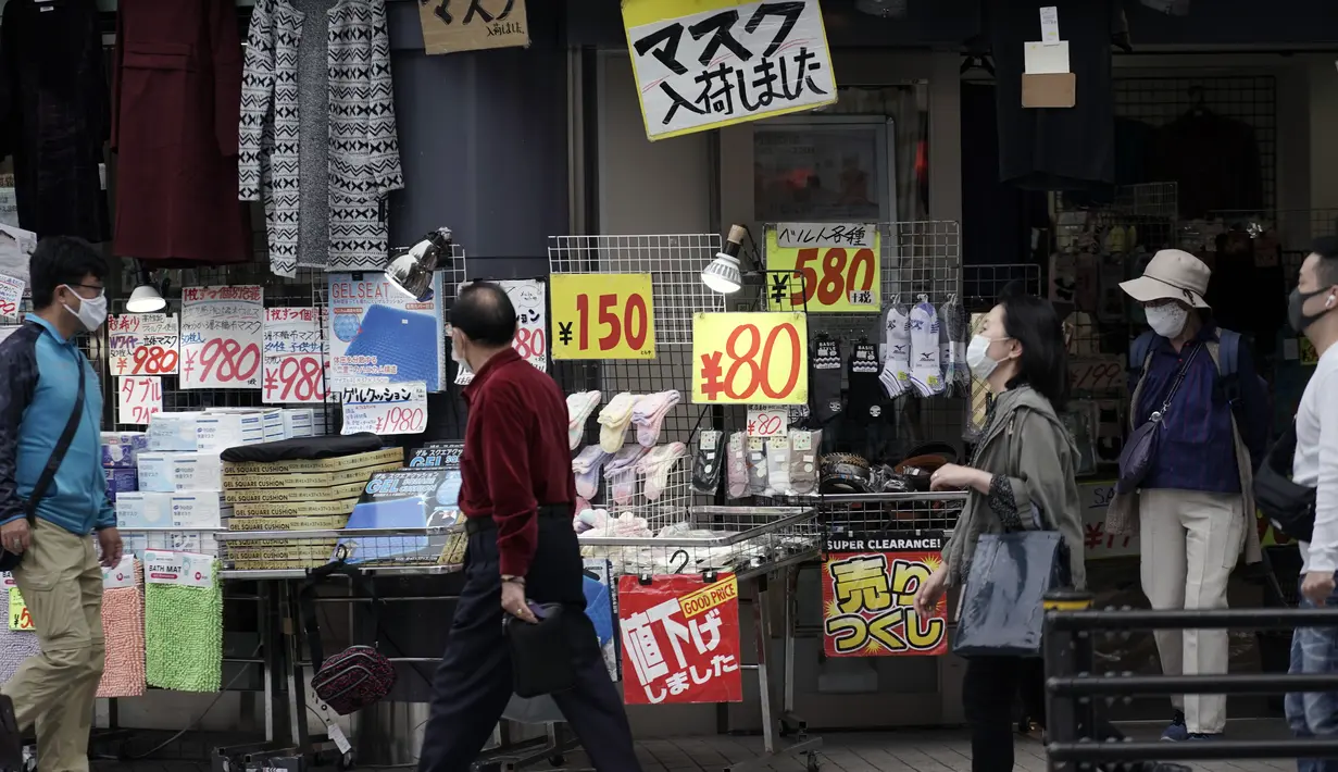 Orang-orang yang mengenakan masker pelindung untuk membantu mengekang penyebaran virus corona berjalan di dekat toko yang menjual masker di Tokyo, Jepang, Rabu (14/10/2020). Tokyo mengonfirmasi lebih dari 170 kasus virus corona baru pada hari Rabu. (AP Photo/Eugene Hoshiko)